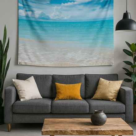 Hawaiian beach tapestry wall hanging with ocean and sky print displayed above a dark grey sofa with yellow accent pillows and wooden coffee table in modern living room