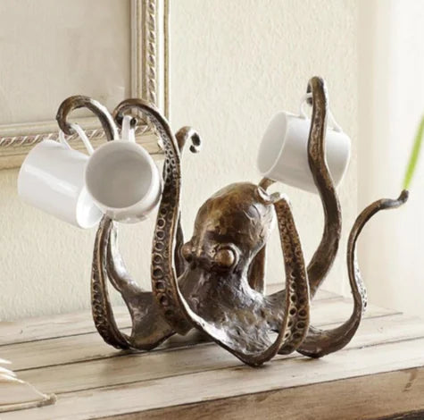 Resin octopus mug holder with lifelike bronze finish, holding white coffee mugs on its tentacles, nautical coastal kitchen décor.