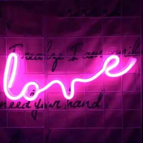 Pink neon light sign with the word love in cursive script