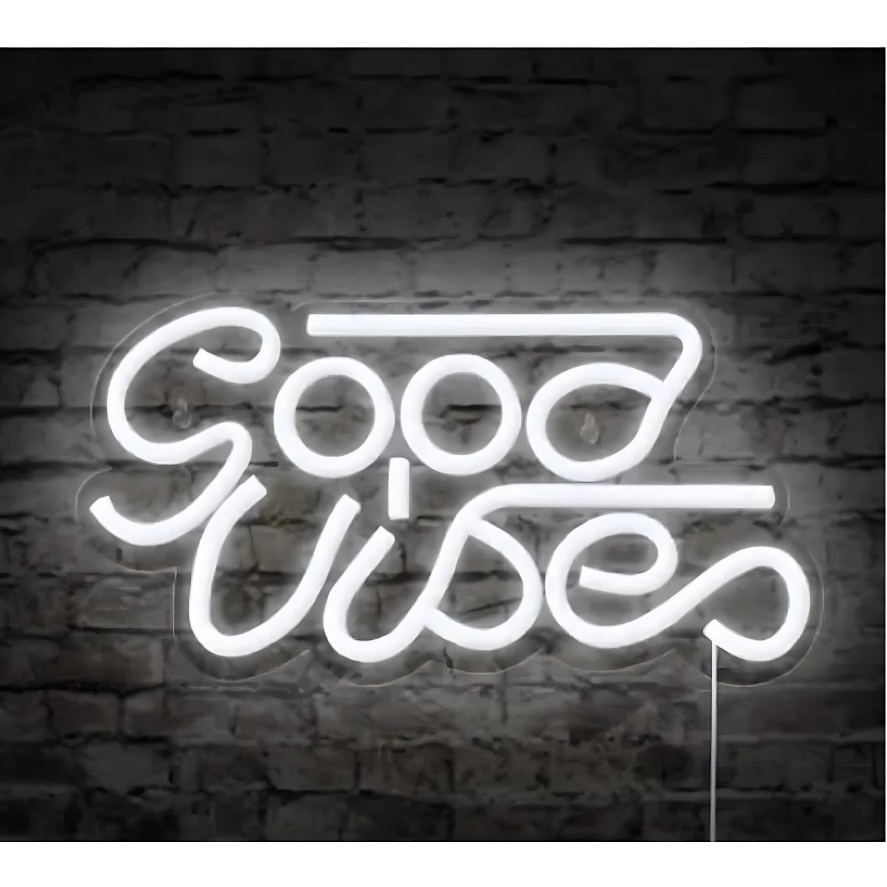 White neon sign spelling “Good Vibes” on a dark brick wall