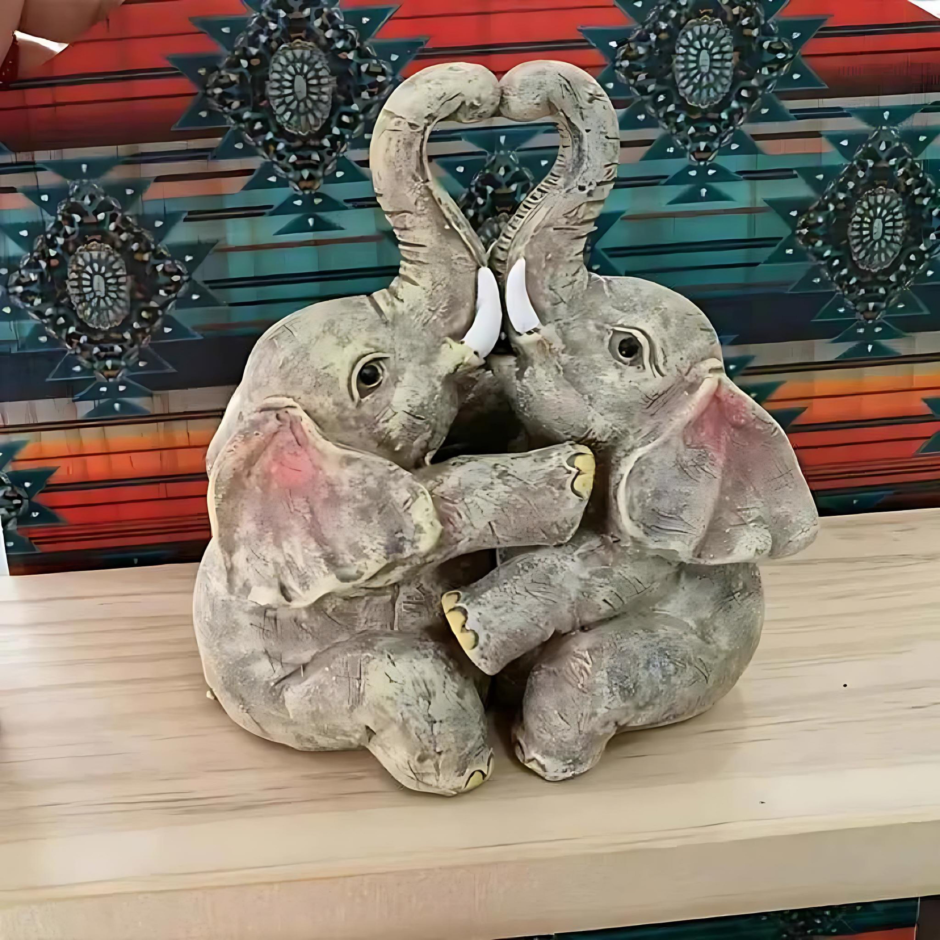 Elephant couple resin figurine with heart-shaped trunks placed in front of a colorful patterned background.