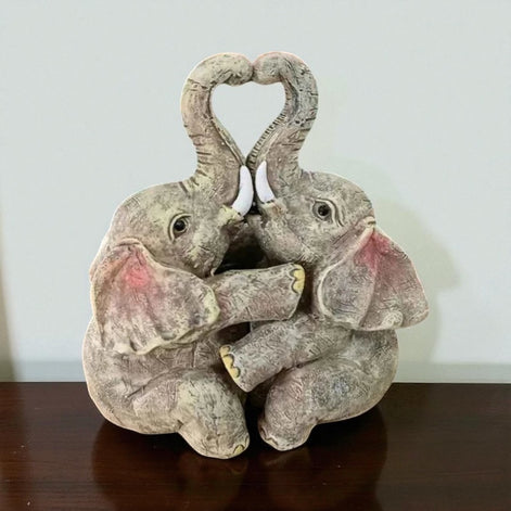 Elephant couple resin figurine forming a heart shape, displayed on a wooden table.