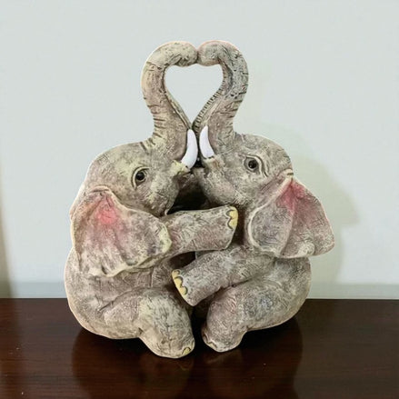 Elephant couple resin figurine forming a heart shape, displayed on a wooden table.
