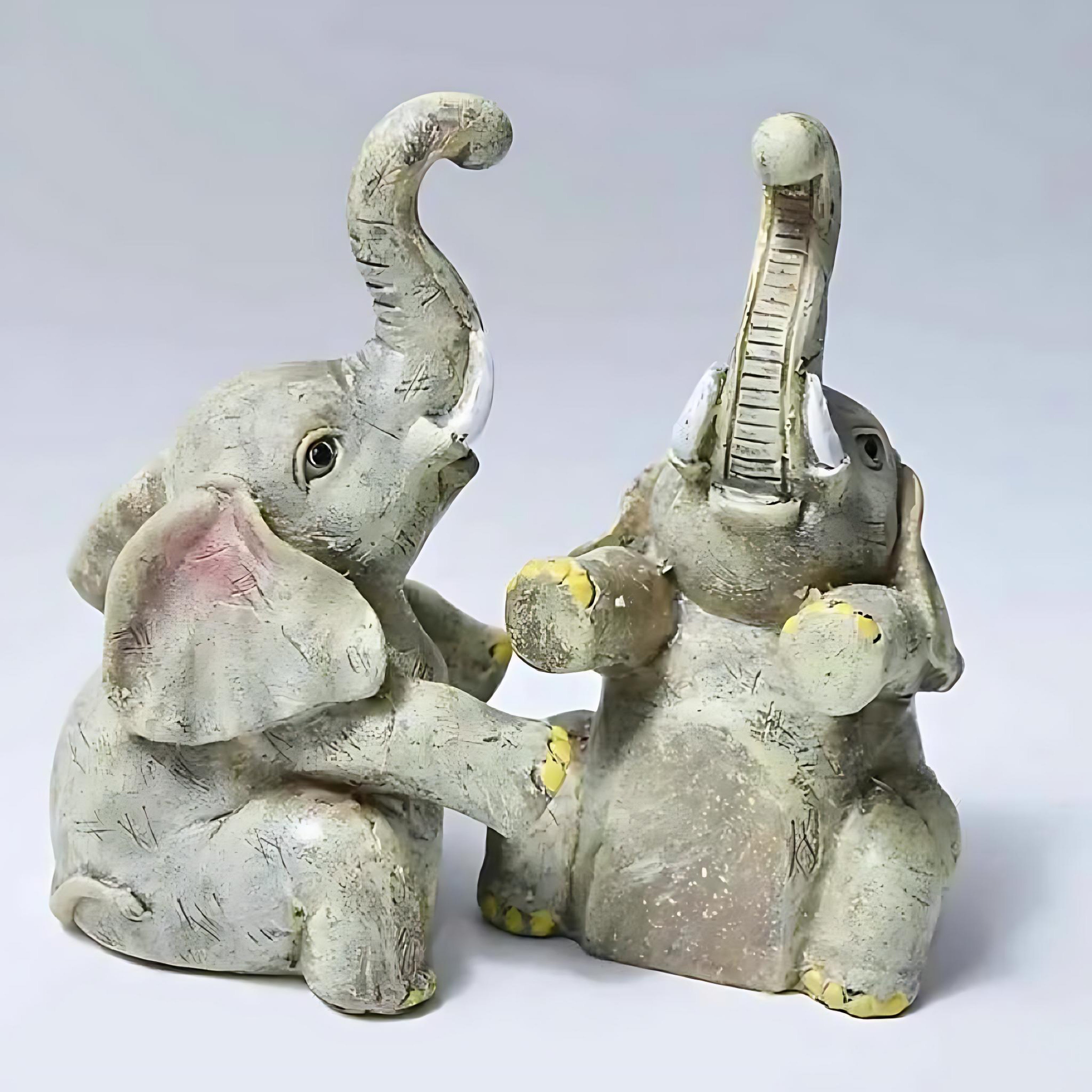 Angled view of resin elephant figurines with raised trunks and textured detailing.
