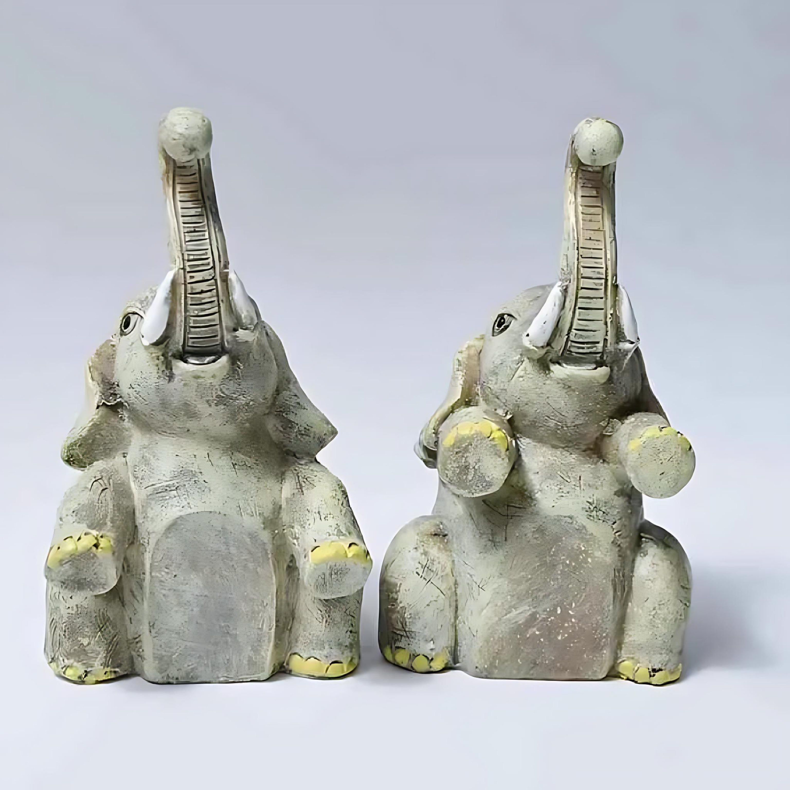Front view of a resin elephant figurine set with raised trunks and rustic finish.