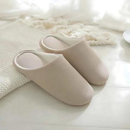Soft cotton-linen beige indoor slippers on a bright tiled floor beside a cozy rug.