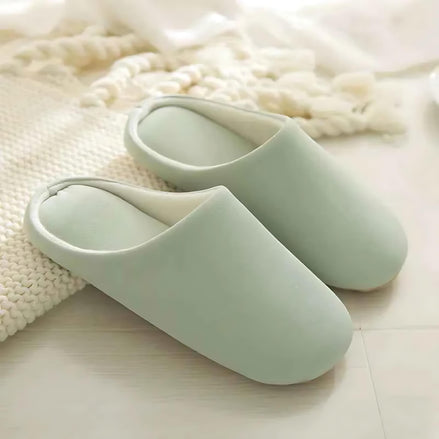 Soft cotton-linen mint green indoor slippers placed near a woven blanket.
