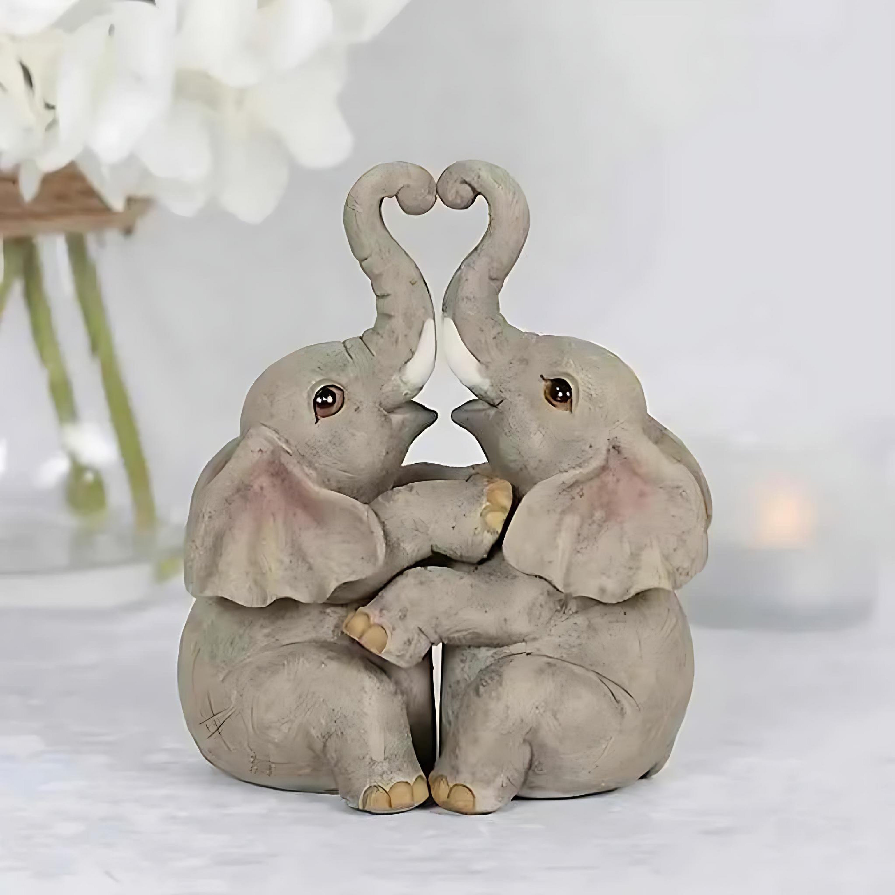 Romantic resin elephant couple figurine with trunks forming a heart, perfect for Valentine’s Day home decor.
